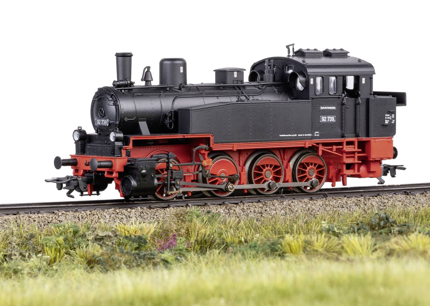 La locomotive à vapeur BR 78 roule sur une section de voie ferrée longeant une prairie. La locomotive a un châssis noir avec des détails rouges.