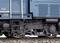 Gros plan d'un essieu de wagon ferroviaire bleu sur des rails. Représentation détaillée des mécanismes et des textures du matériel roulant ferroviaire.