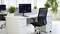 Bureau moderne avec deux bureaux, chacun équipé d'un ordinateur affichant des graphiques de performance. Une chaise de bureau et des plantes en pot complètent la décoration.