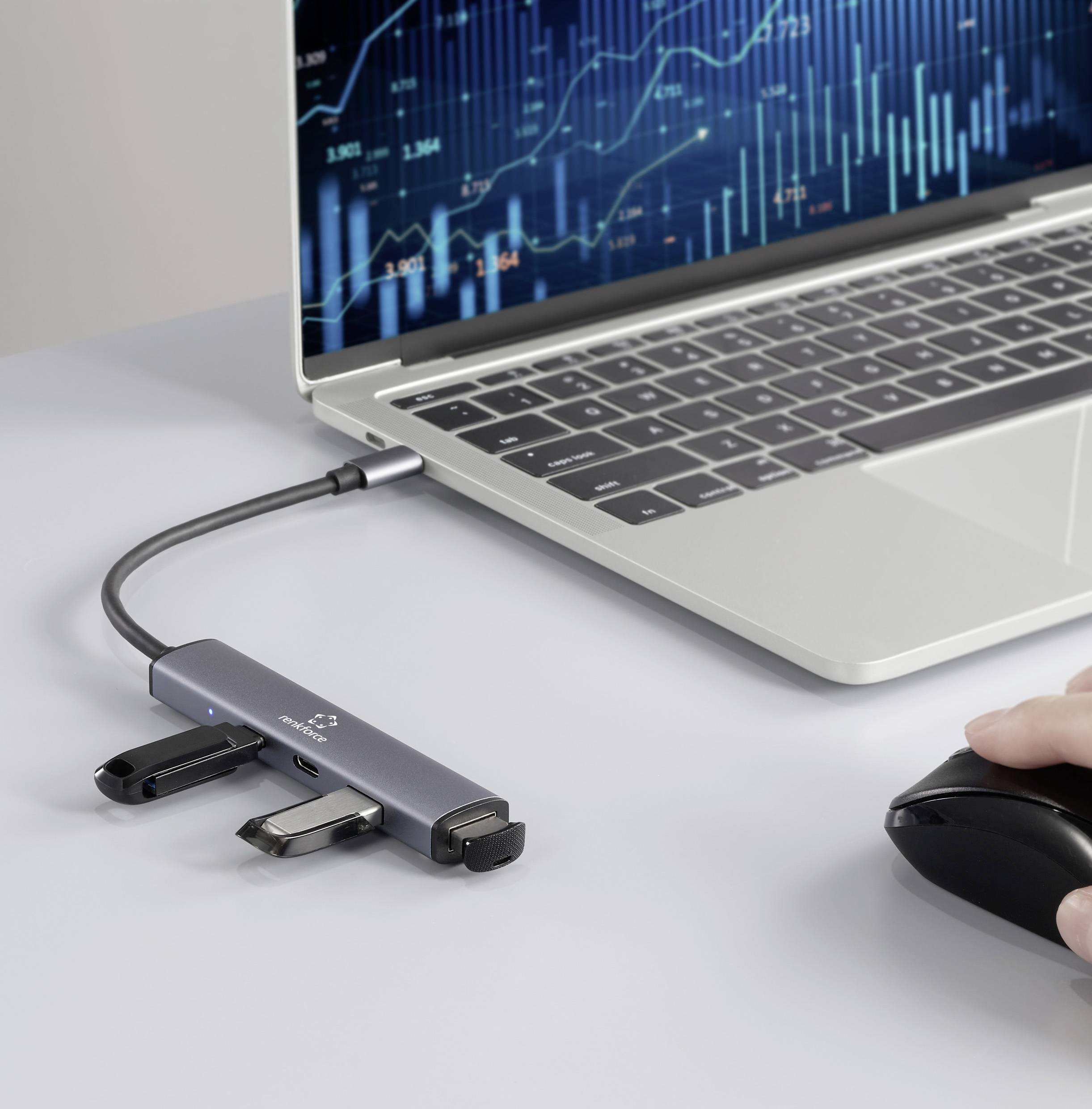 Un ordinateur portable connecté à un hub multiport avec des périphériques USB, une main utilisant une souris ; sur l'écran, un graphique linéaire numérique avec des lignes de données bleues fluctuantes.