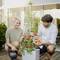 Un homme et une femme récoltent des tomates d'une plante sur une terrasse. Ils ont l'air satisfaits et tiennent un panier de tomates.