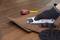 Une main gantée utilise un couteau utilitaire pour couper une pièce de stratifié au motif de bois sur une table. Un mètre ruban est visible en arrière-plan.
