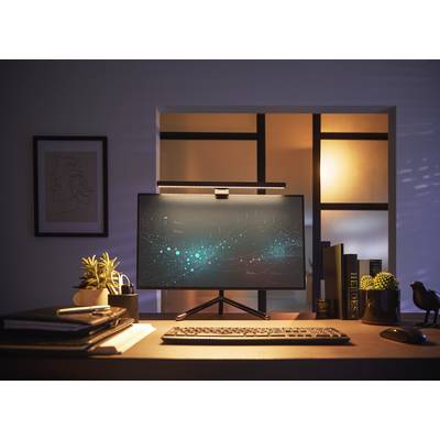 Un écran d'ordinateur sur un bureau affiche une visualisation de données numériques. Des plantes et des livres se trouvent également sur la table.