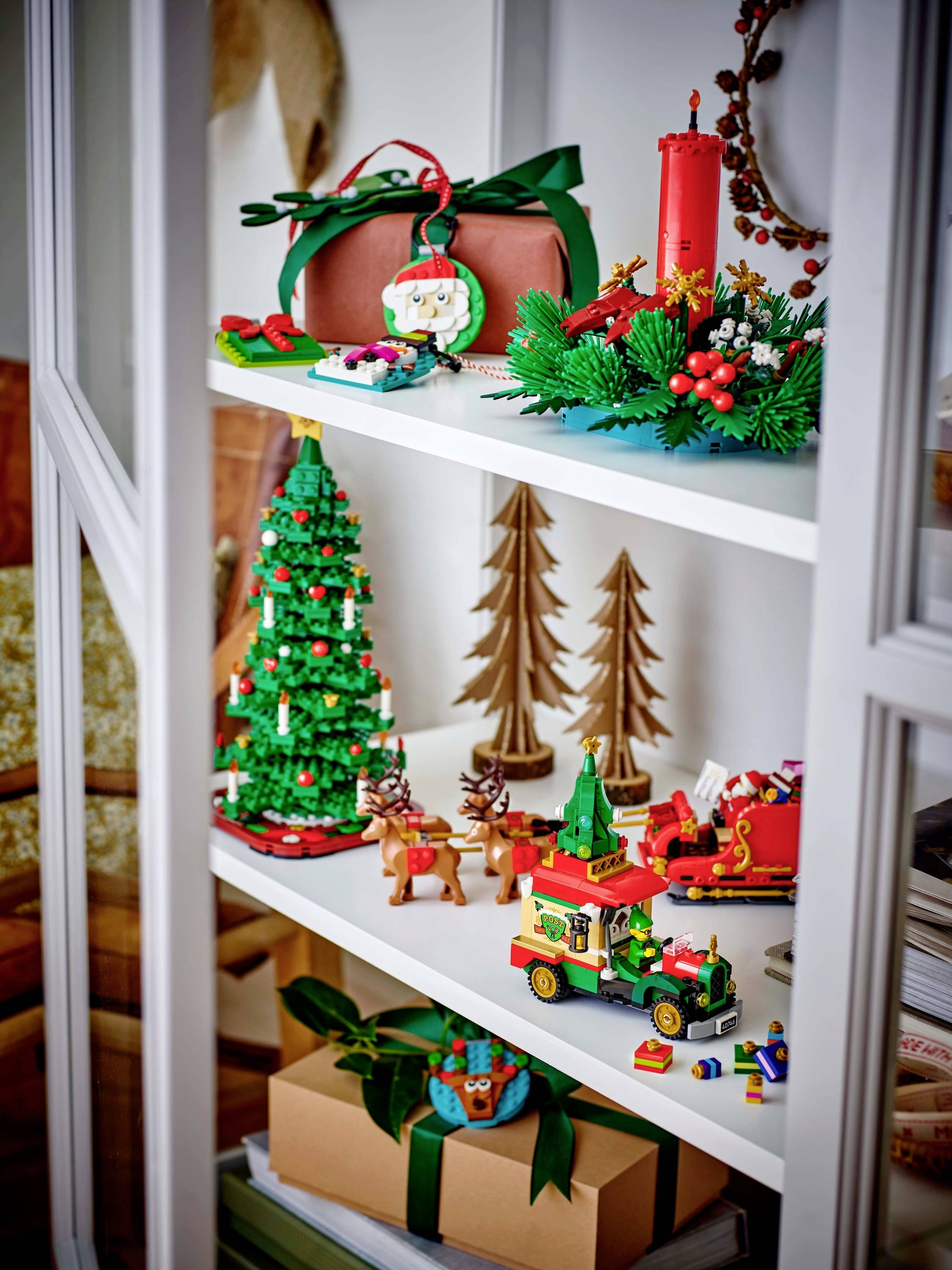 Une étagère décorée avec des ornements de Noël comprenant un train miniature, un petit sapin de Noël, des rennes et diverses figurines festives.