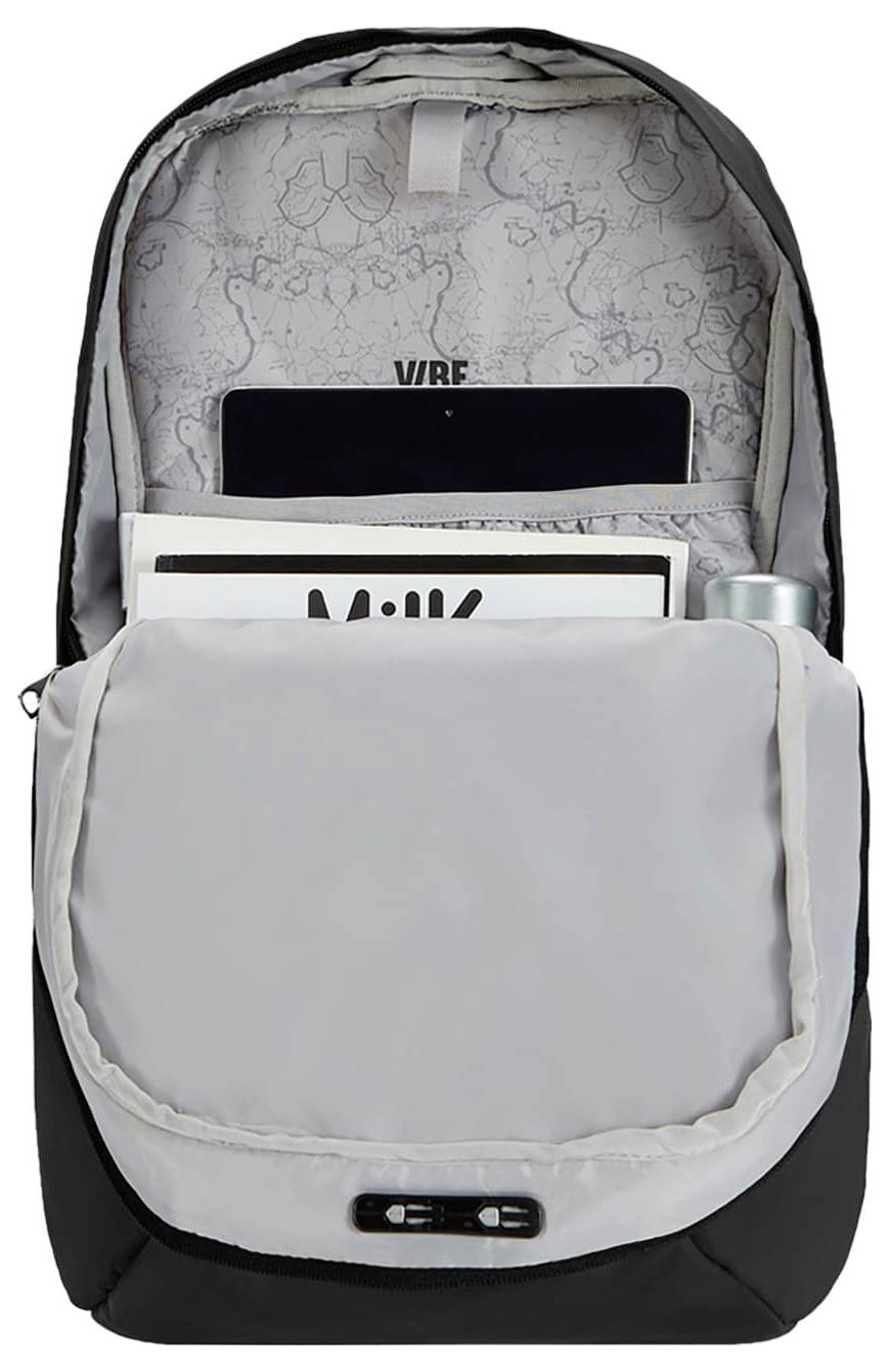 Un sac à dos ouvert montrant un intérieur avec des compartiments contenant une tablette, un magazine et un objet cylindrique, présentant un motif à l'intérieur.