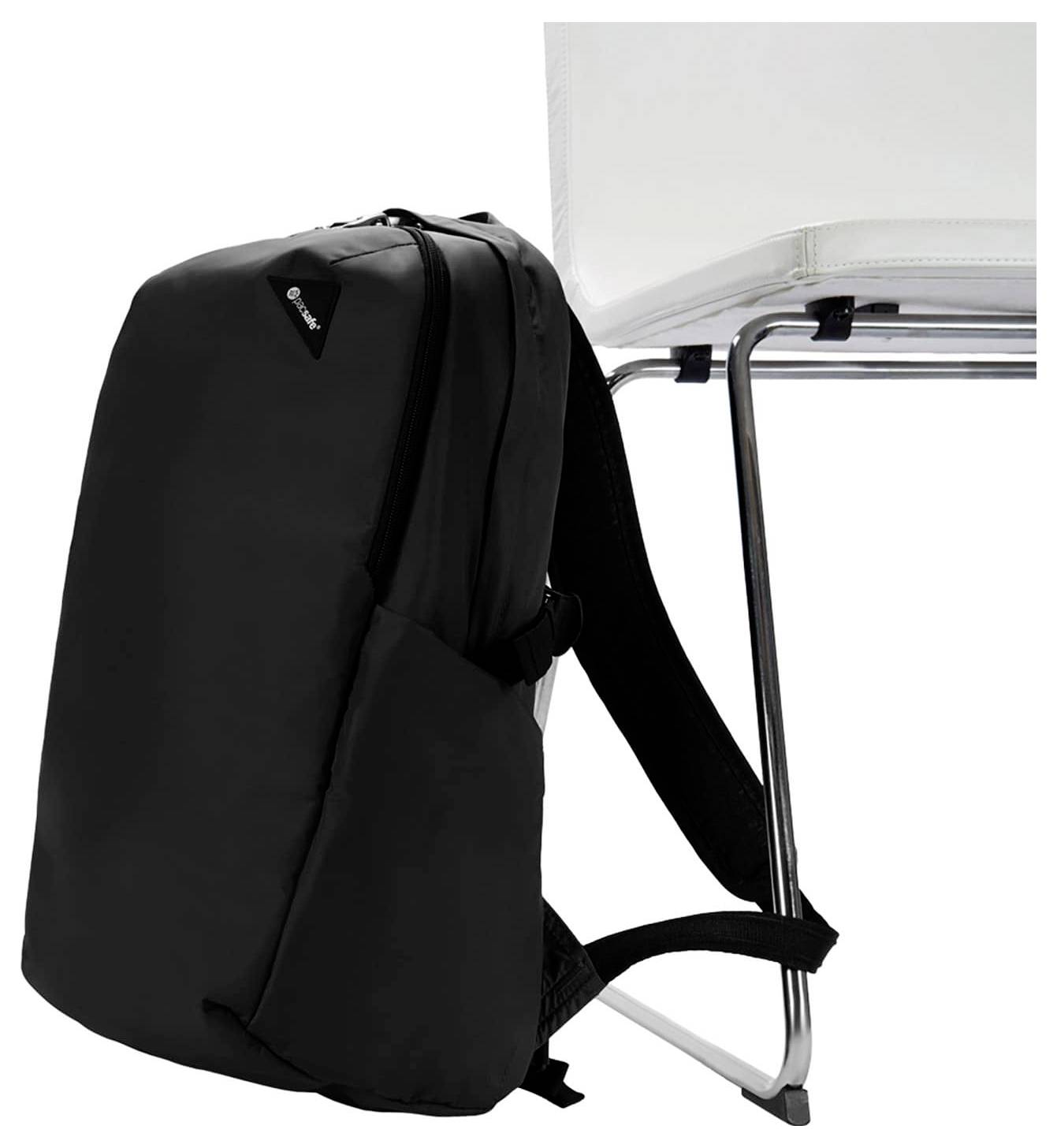 Un sac à dos noir est placé verticalement sur une chaise blanche, mettant en valeur son design épuré et son logo de marque visible près du sommet.