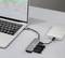Un ordinateur portable connecté à un hub avec trois appareils USB, à côté d'un disque dur externe. L'écran de l'ordinateur portable affiche un graphique linéaire.