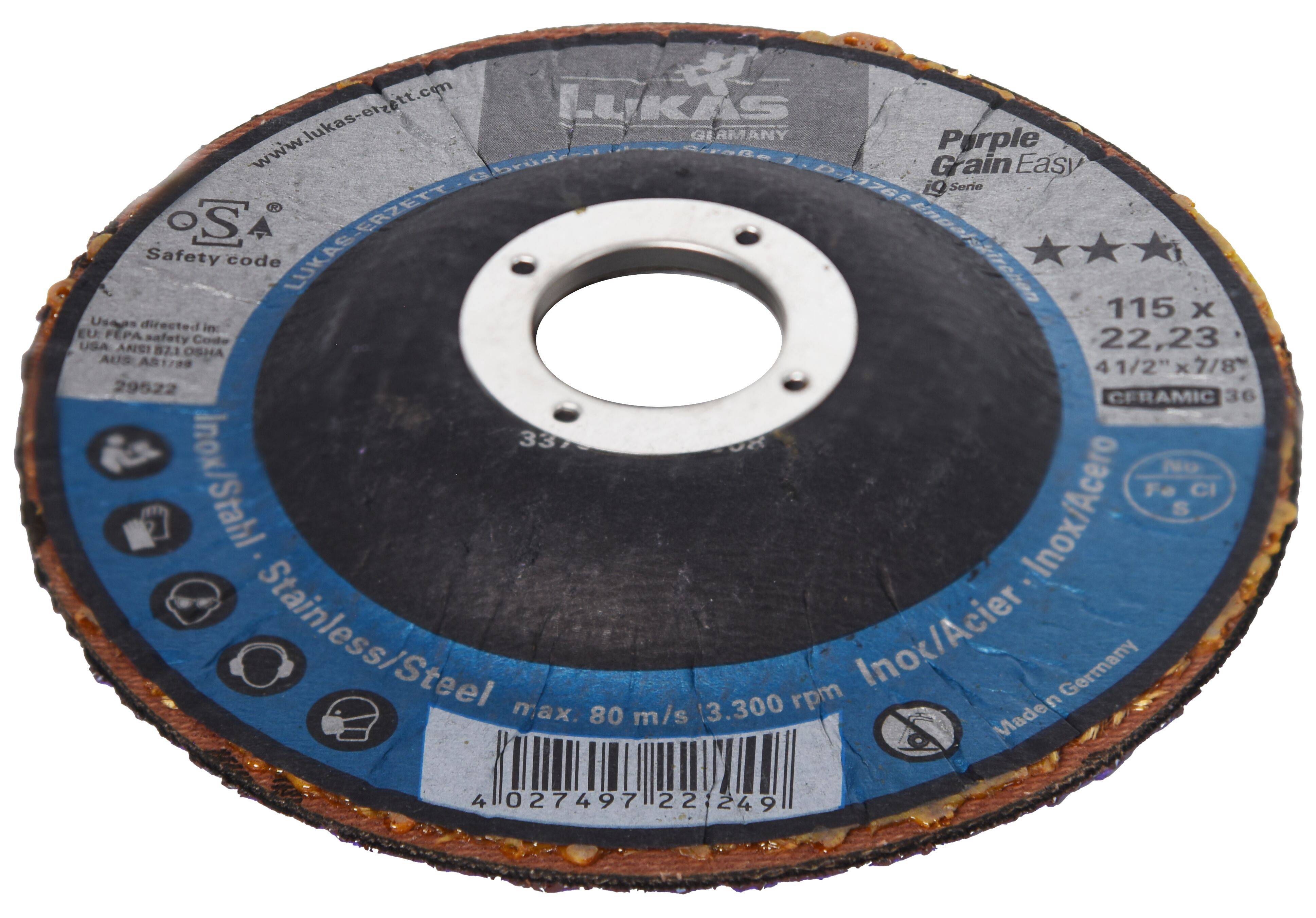 Un disque de meulage circulaire avec un trou central, étiqueté pour une utilisation sur l'acier inoxydable. Le disque est coloré avec divers marquages de sécurité et d'utilisation.