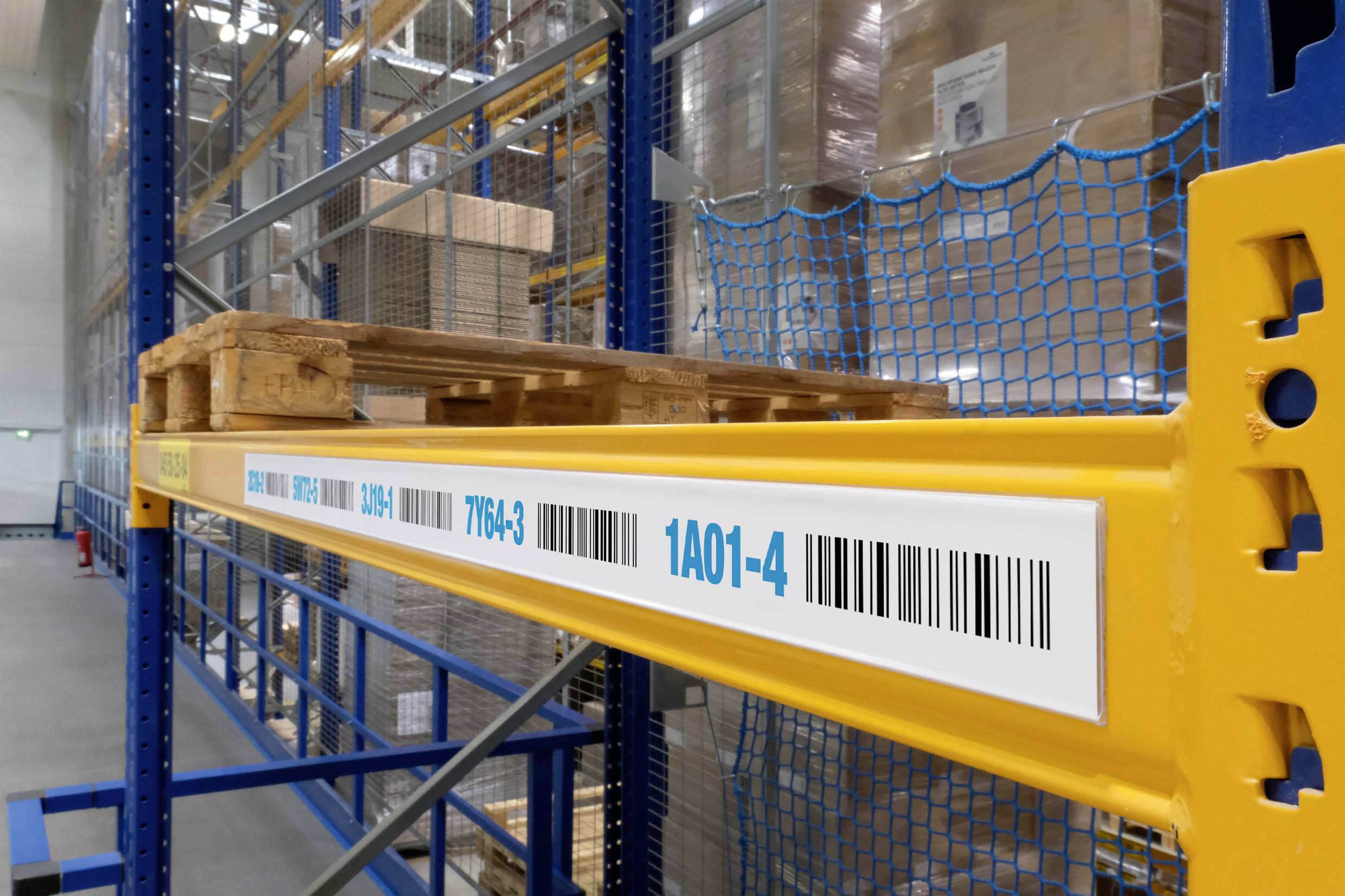 Étagère d'entrepôt avec une palette rangée sur une étagère métallique haute, portant une étiquette avec code-barres numérotée pour la gestion des stocks.