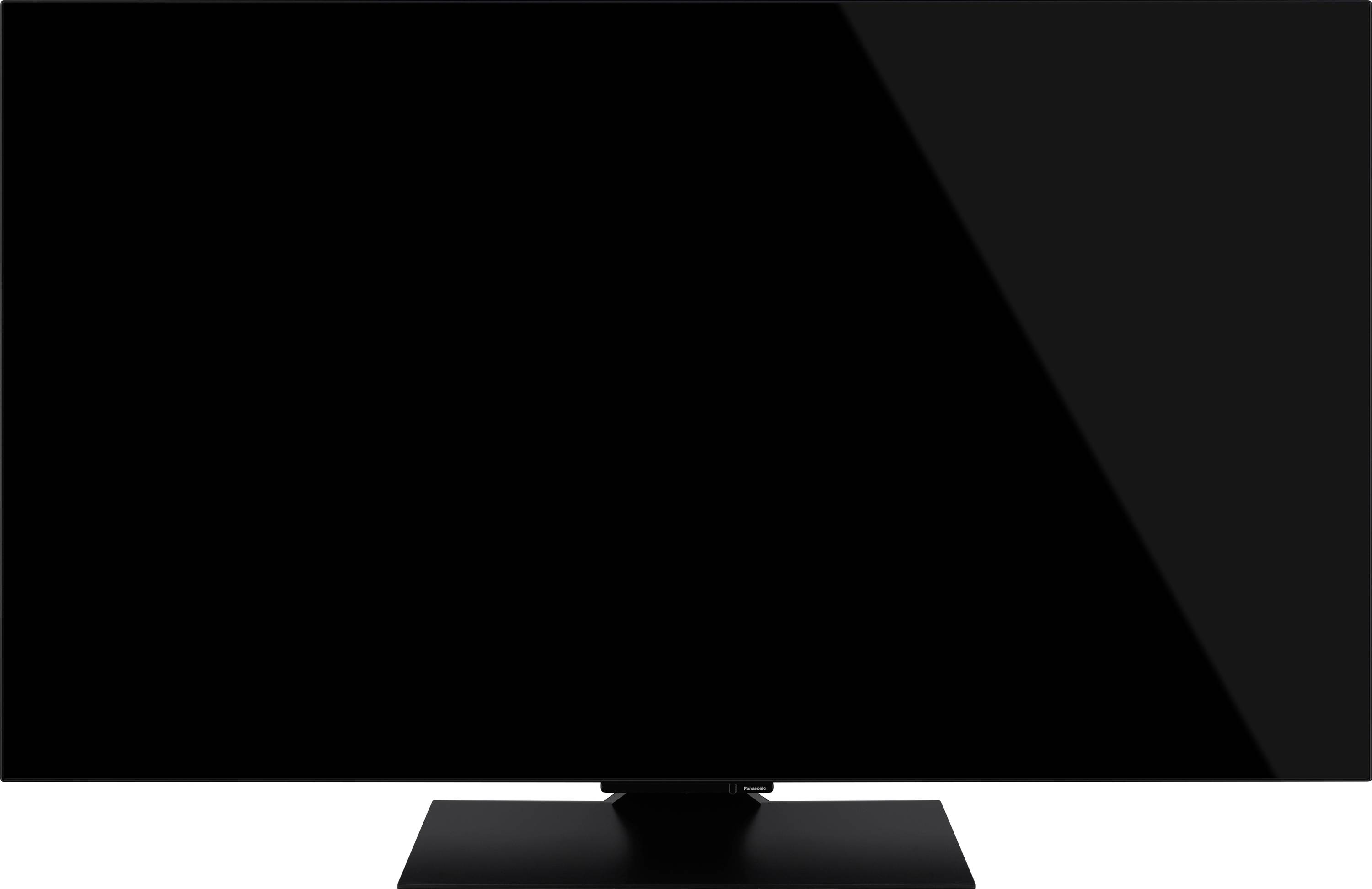 Un grand téléviseur noir à écran plat éteint, posé sur un support rectangulaire, dans un environnement neutre.