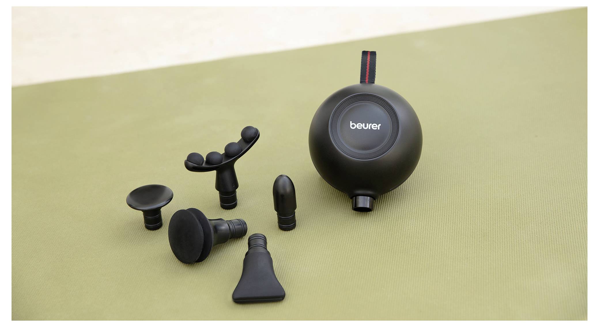 Un appareil de massage doté de plusieurs embouts interchangeables est posé sur une surface.