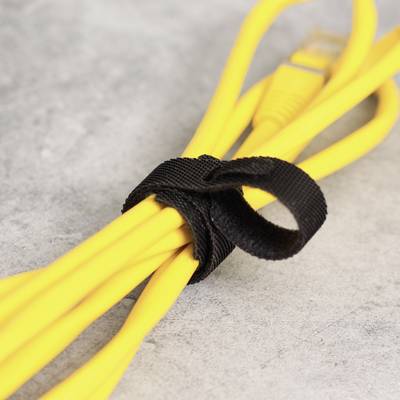 Un câble réseau jaune bouclé et maintenu par une sangle Velcro noire, posé sur une surface grise.