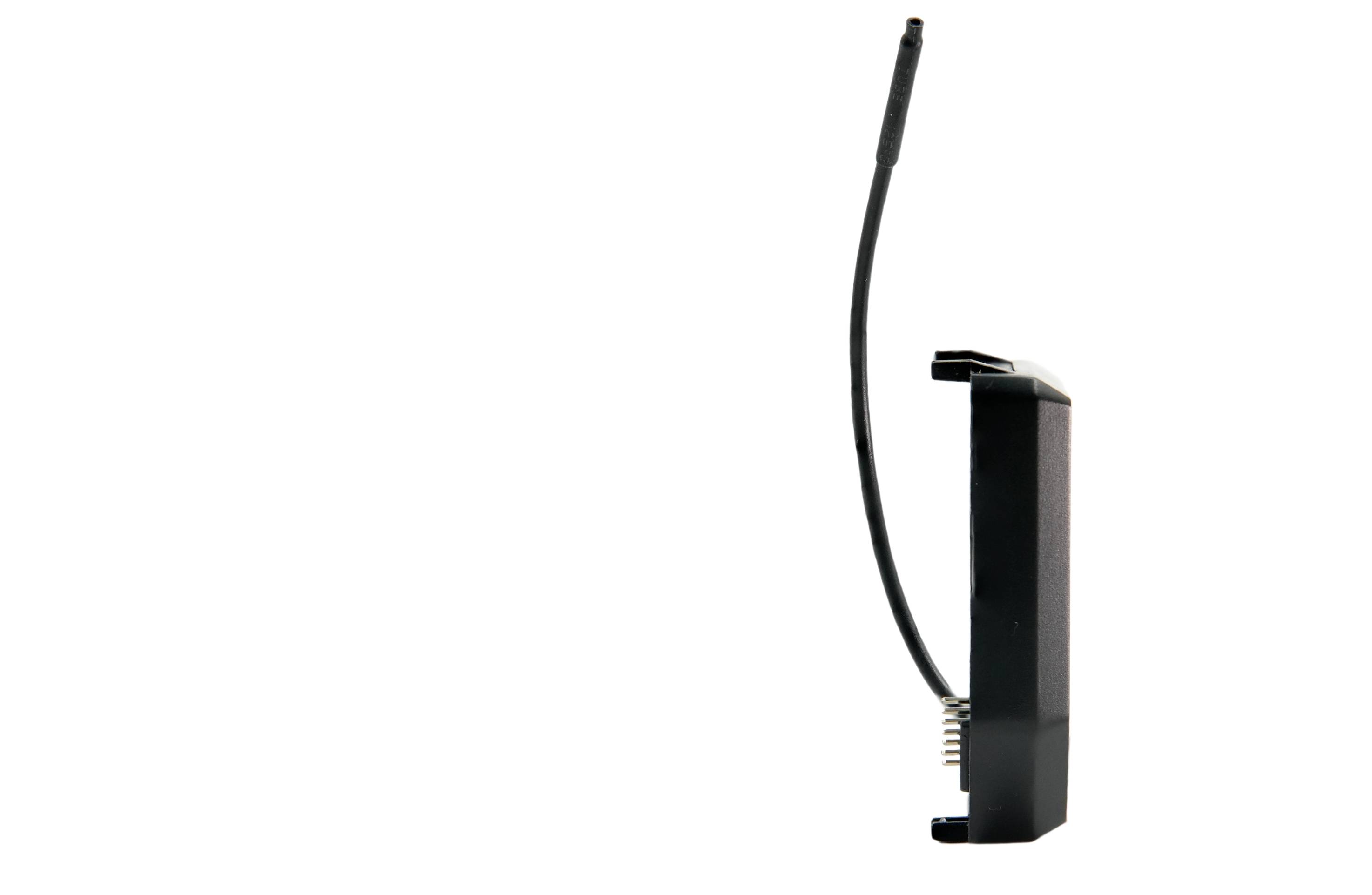 Un dispositif compact noir avec une antenne et des broches, probablement un module sans fil ou un capteur, positionné sur le côté contre un arrière-plan uni.