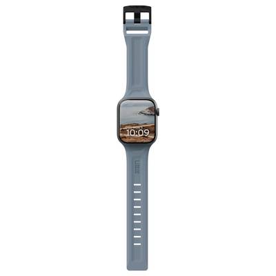 Une montre connectée avec un bracelet bleu affiche l'heure '10:09' et montre un paysage pittoresque d'une côte rocheuse et des vagues océaniques sur l'écran.