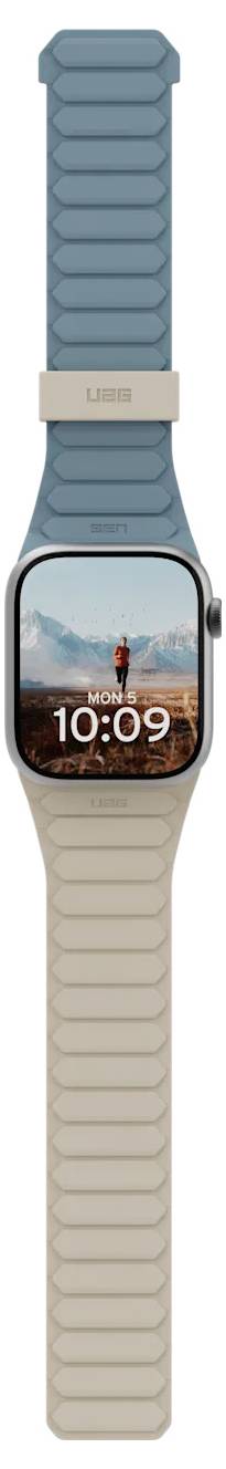 Une montre connectée avec un bracelet beige et bleu sarcelle affiche '10:09' sur l'écran, montrant un arrière-plan de paysage de montagne pittoresque.
