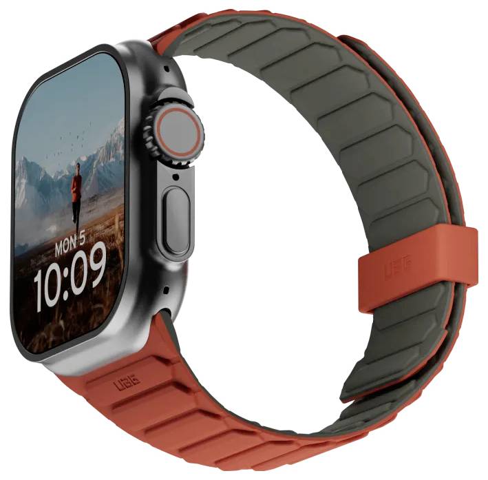 Une montre connectée avec un écran rectangulaire affichant 'Lun 5, 10:09' et un arrière-plan de paysage montagneux. Elle est équipée d'un bracelet en caoutchouc gris et rouge.