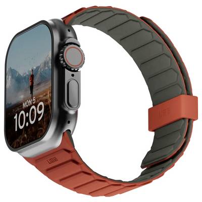 Une montre connectée avec un écran rectangulaire affichant 'Lun 5, 10:09' et un arrière-plan de paysage montagneux. Elle est équipée d'un bracelet en caoutchouc gris et rouge.