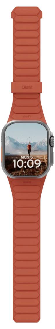 Une montre connectée avec un bracelet orange vif affiche l'heure '10:09'. L'écran montre un randonneur sur une montagne avec un ciel bleu clair.