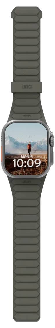 Une montre connectée affichant l'heure '10:09' sur son écran avec un randonneur et un paysage de montagne en arrière-plan. La montre a un bracelet foncé.