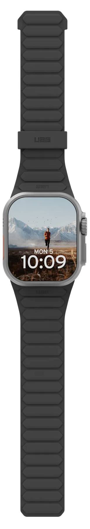Une montre connectée avec un bracelet noir affiche l'heure '10:09' et une image de fond représentant une personne debout sur un sommet de montagne sous un ciel bleu.