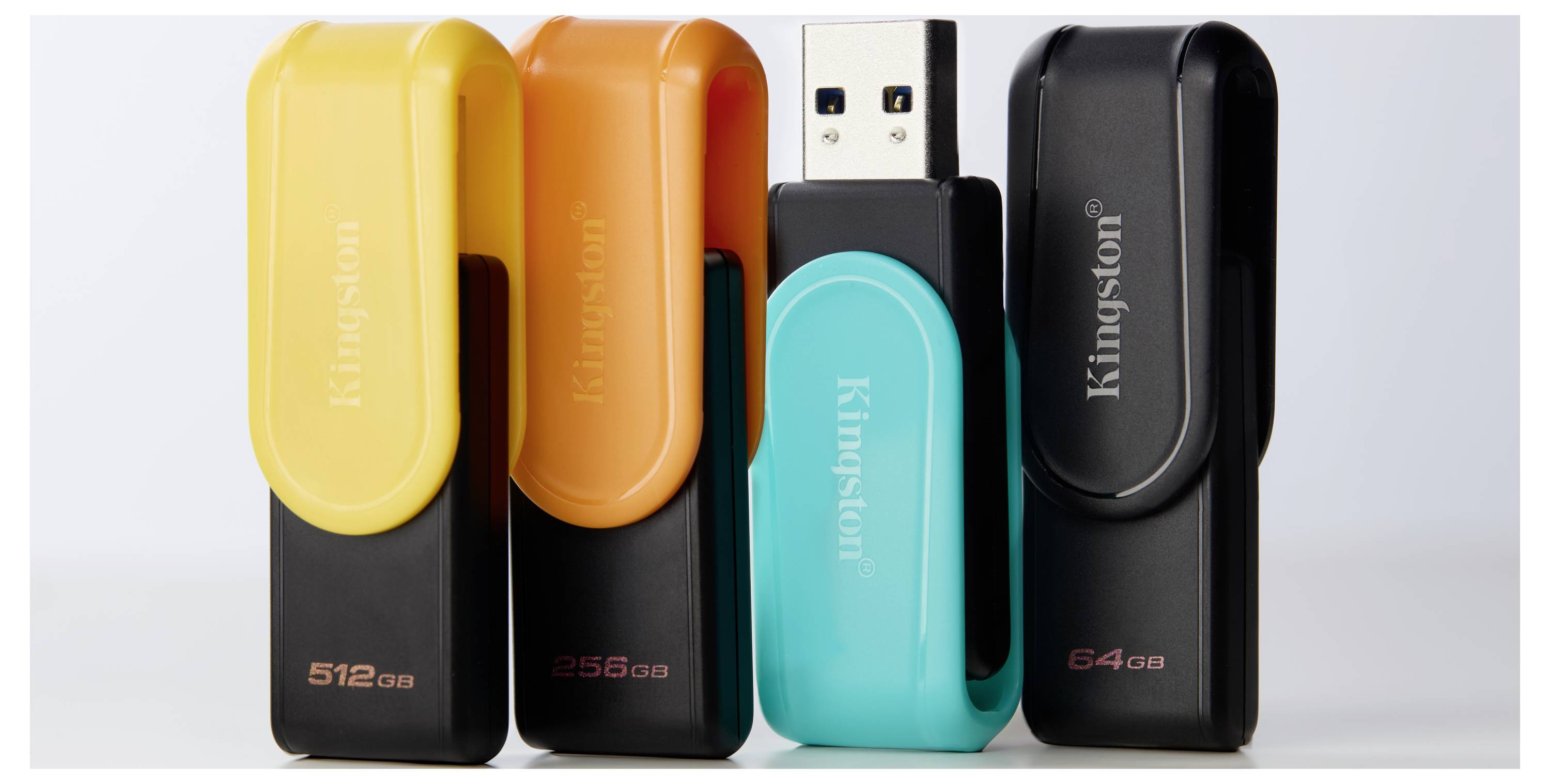 Quatre clés USB Kingston de différentes couleurs (jaune, orange, bleu sarcelle et noir) sont debout, chacune étiquetée avec des capacités de stockage : 512 Go, 256 Go et 64 Go.