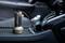 Un dispositif cylindrique muni d'une poignée tactique est posé sur la console centrale d'une voiture. Il est relié par un câble, ce qui suggère une fonctionnalité électronique.