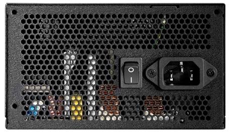 Gros plan sur un bloc d'alimentation d'ordinateur montrant un interrupteur marche/arrêt, un port de connexion de câble et des composants internes derrière une grille perforée.