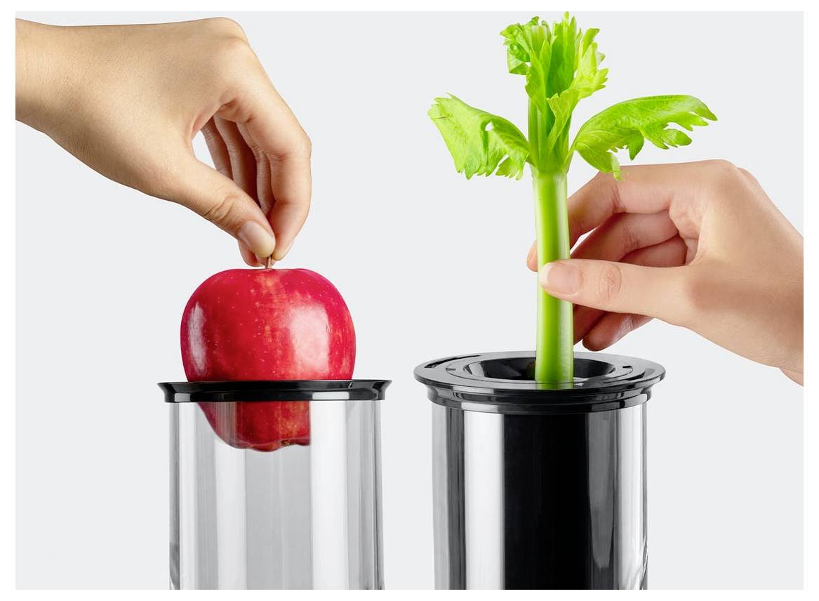 Une main dépose une pomme dans un grand récipient noir sur la gauche, tandis qu'une autre main tient une tige de céleri au-dessus d'un récipient similaire sur la droite.