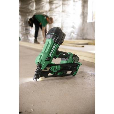 Un cloueur sans fil HiKOKI vert est positionné, avec des ouvriers du bâtiment et des poutres en bois visibles en arrière-plan flou d'un chantier de construction.