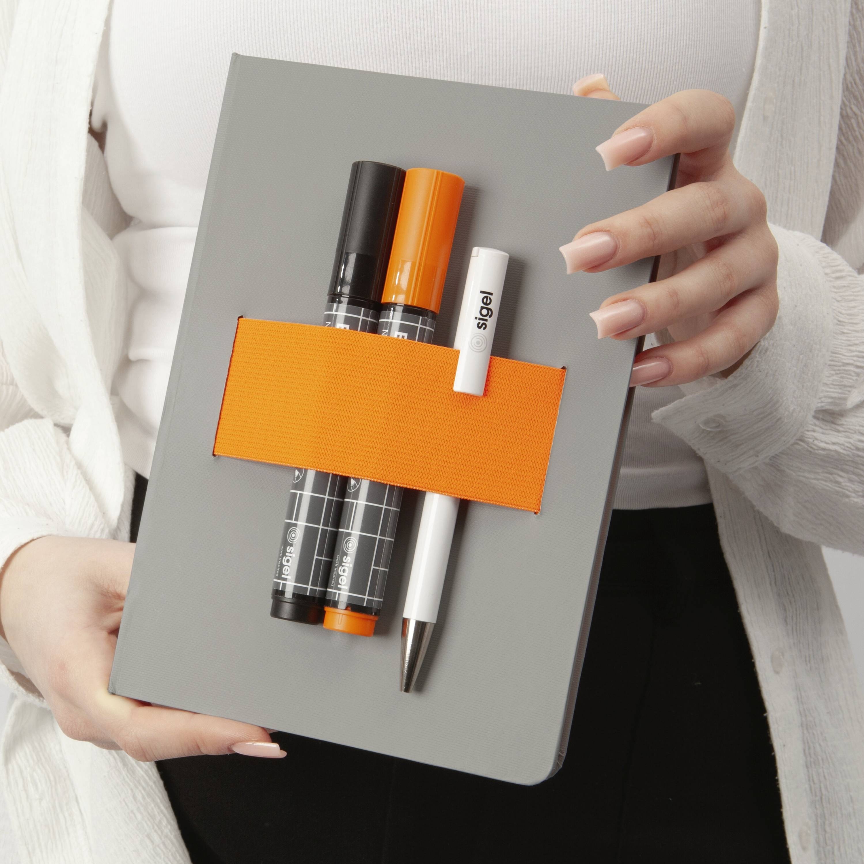 Une personne tenant une boîte grise avec une bande orange vive, contenant deux marqueurs et un stylo blanc. Le haut du corps de la personne est partiellement visible.