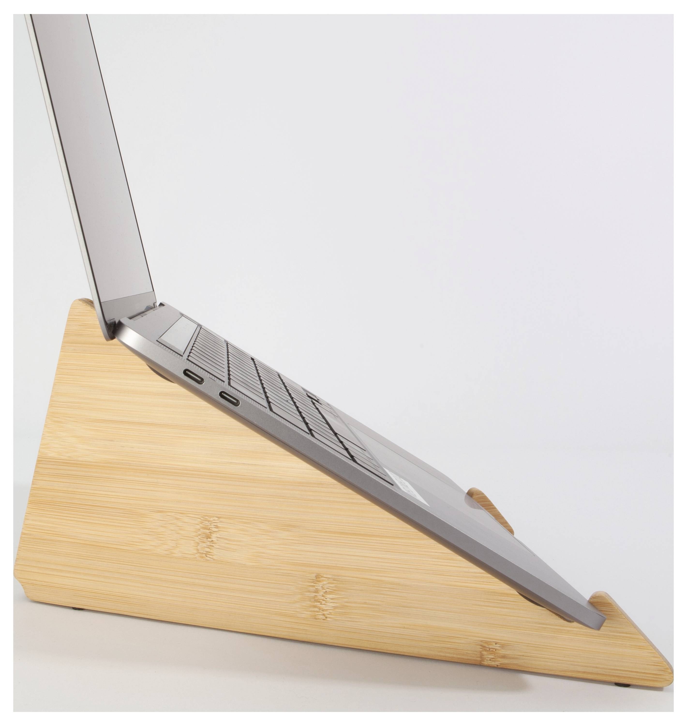 Vue de côté d'un ordinateur portable fermé reposant sur un support en coin en bois, avec l'écran partiellement ouvert.