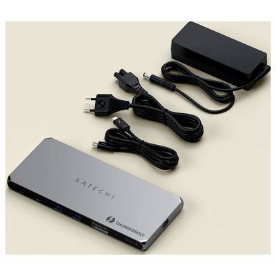 Un adaptateur de station d'accueil Satechi Thunderbolt avec son adaptateur secteur et ses câbles est disposé sur une surface beige.