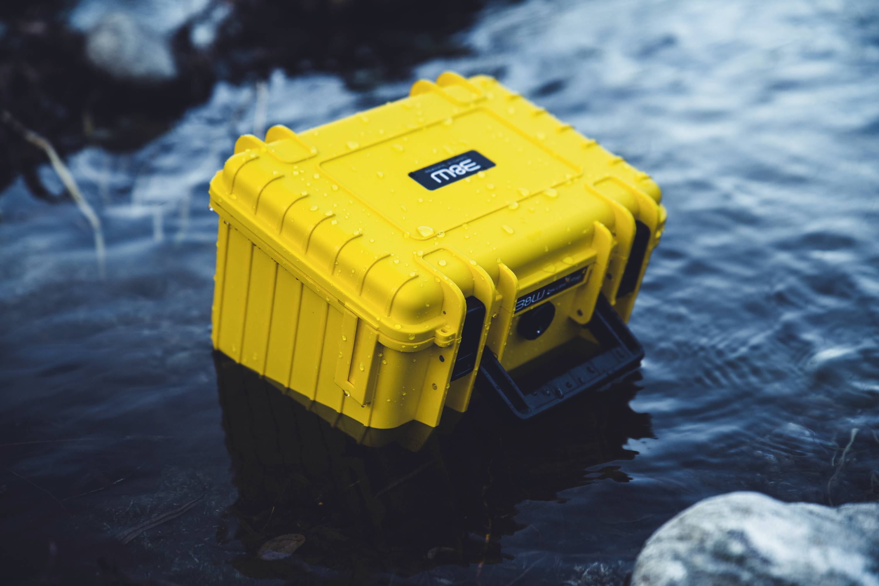 Un étui étanche jaune flottant dans un plan d'eau, indiquant sa durabilité et sa résistance à l'eau.