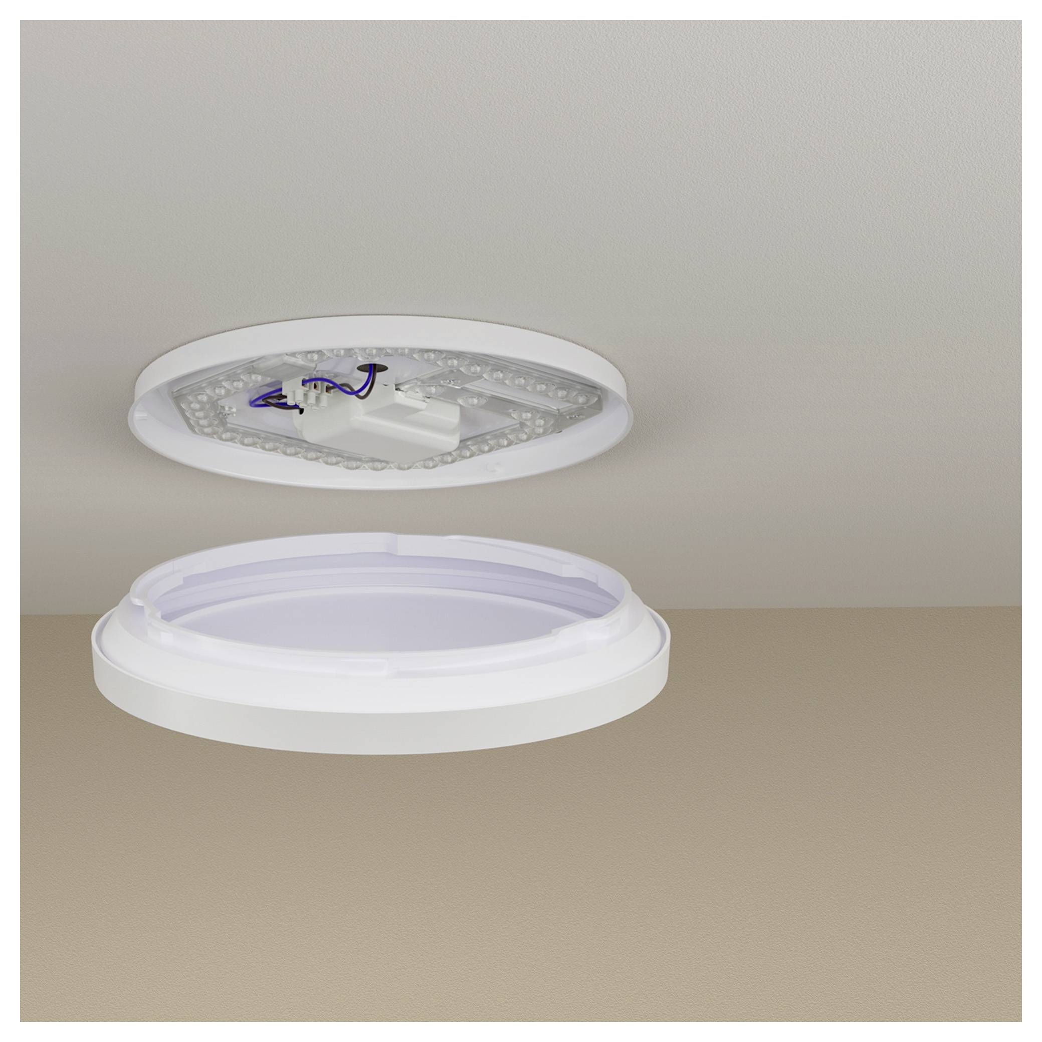 Un plafond est montré avec un luminaire de plafond à LED rond détaché. Le luminaire est blanc avec des LED apparentes et une base vide.