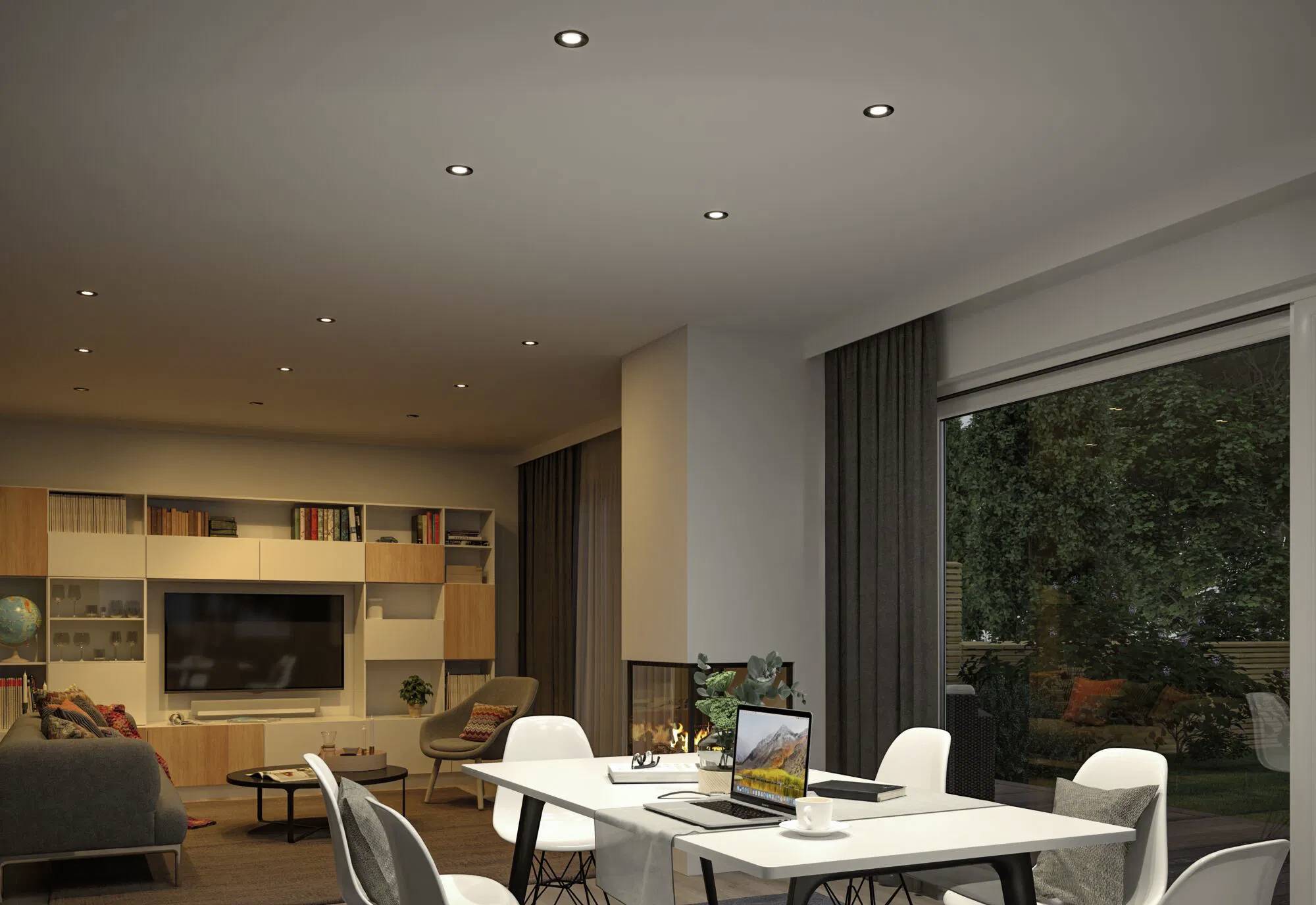 Un salon et une salle à manger modernes avec un canapé, des étagères à livres, une télévision, une table à manger et des chaises. Une grande fenêtre donne sur un jardin extérieur.