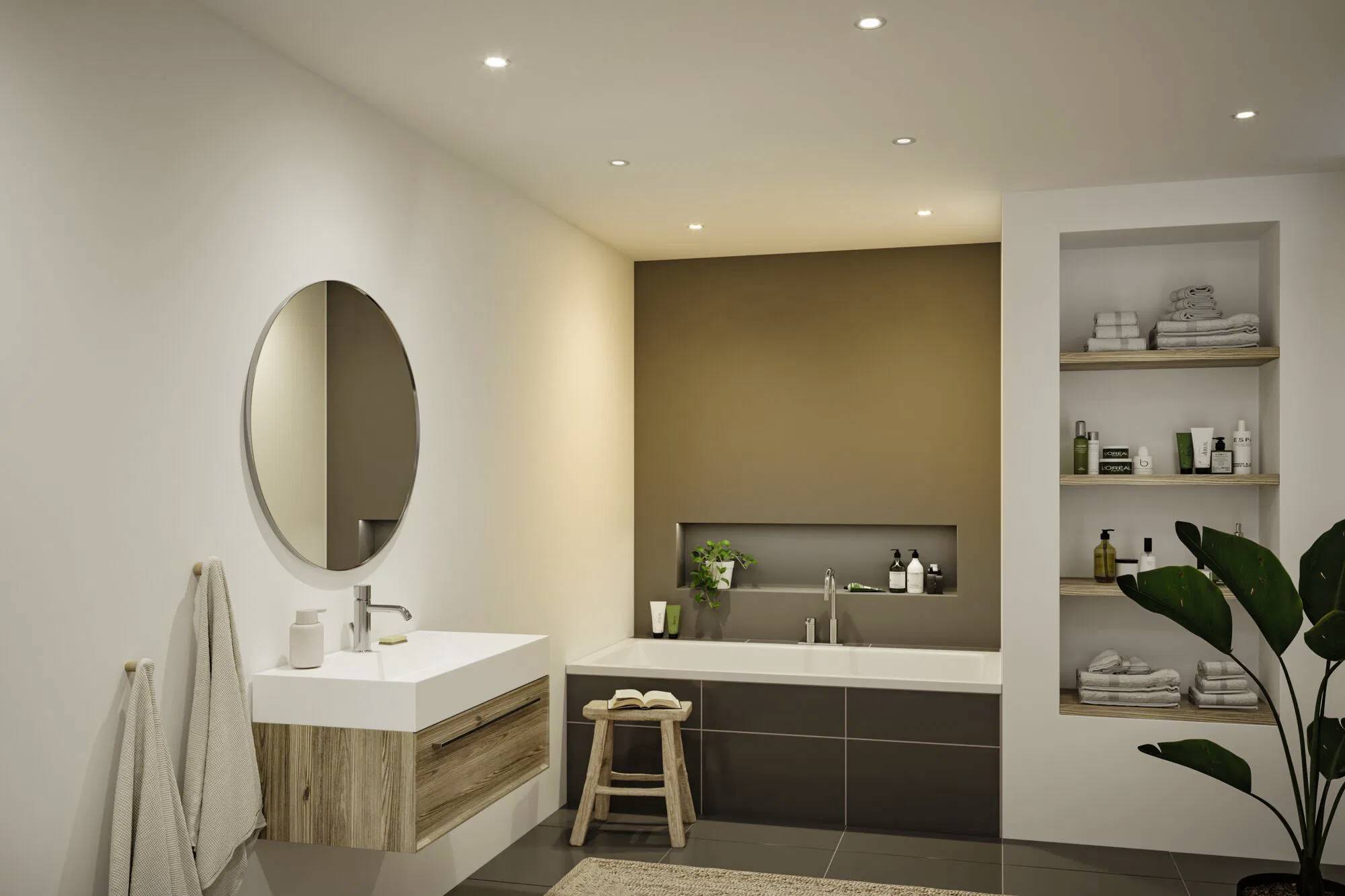 Salle de bain moderne avec un miroir circulaire au-dessus d'un lavabo en bois, une baignoire avec divers produits de toilette, et des étagères ouvertes avec des serviettes sur la droite.