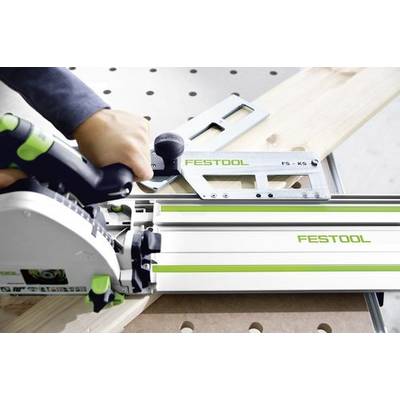 Une personne utilise un outil Festool sur une planche de bois, positionnée sur un établi. L'outil semble être un guide de scie, aidant à la coupe de précision.