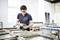 Un homme portant des lunettes de sécurité travaille à la restauration de cadres de fenêtres en bois dans un atelier bien éclairé, se concentrant sur un artisanat précis.