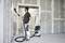 Une personne ponce un mur à l'aide d'une ponceuse électrique à long manche, raccordée à un aspirateur, dans une pièce partiellement aménagée avec du placoplâtre.