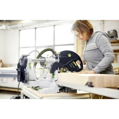 Une personne portant des lunettes de sécurité utilise une scie circulaire, en coupant une planche de bois dans un atelier.