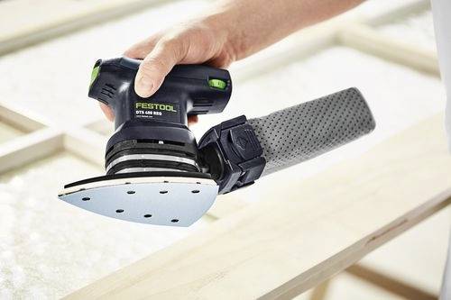 Une personne utilise un outil de ponçage Festool avec un plateau triangulaire pour lisser une surface en bois.
