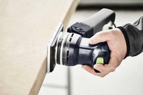 Une personne utilise une ponceuse électrique portative sur une surface en bois, la lissant uniformément avec un souci de savoir-faire et de précision.