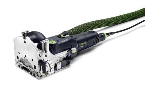 Un outil électrique au corps vert et noir, équipé d'un tuyau d'extraction de poussière, utilisé pour des coupes de précision en menuiserie.