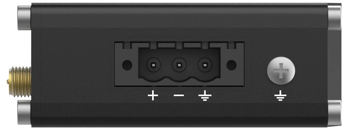 Un dispositif électronique noir présente un connecteur central à trois broches. Un symbole de terre et un signe plus-moins sont étiquetés en dessous.