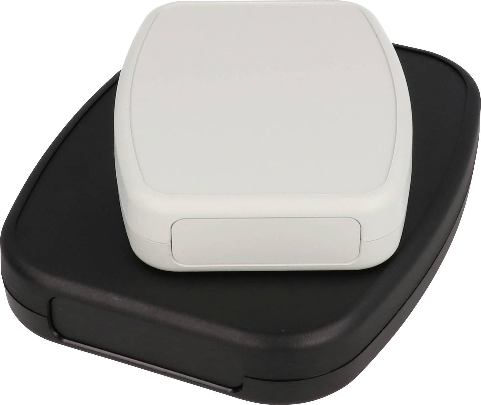 Un objet blanc placé sur le dessus d'un objet noir plus grand, tous deux avec des bords arrondis et des surfaces lisses, probablement des appareils électroniques.
