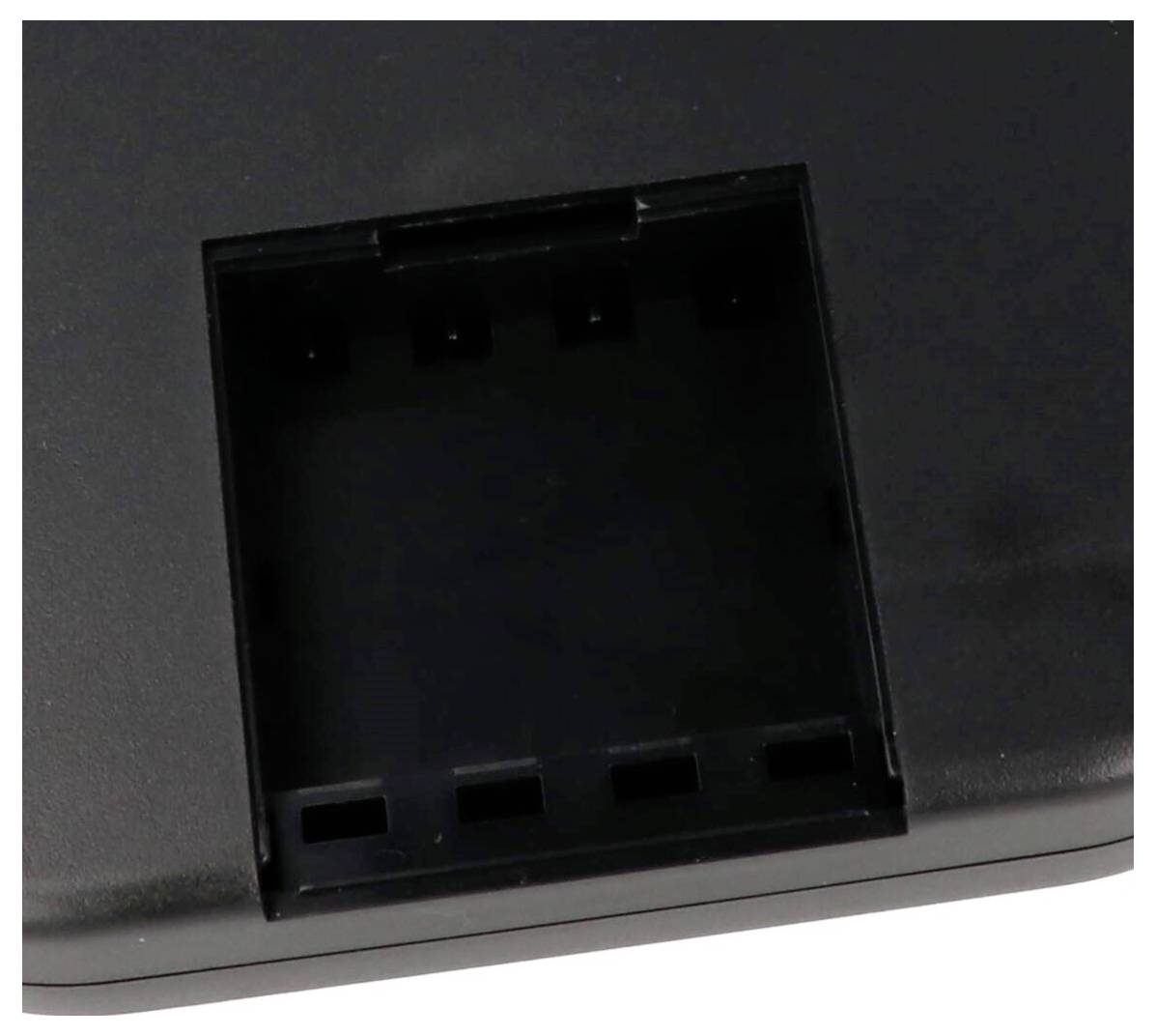 Un gros plan d'une fente rectangulaire noire sur un appareil électronique, probablement destinée à l'insertion de batteries ou d'un composant, avec six connecteurs visibles.