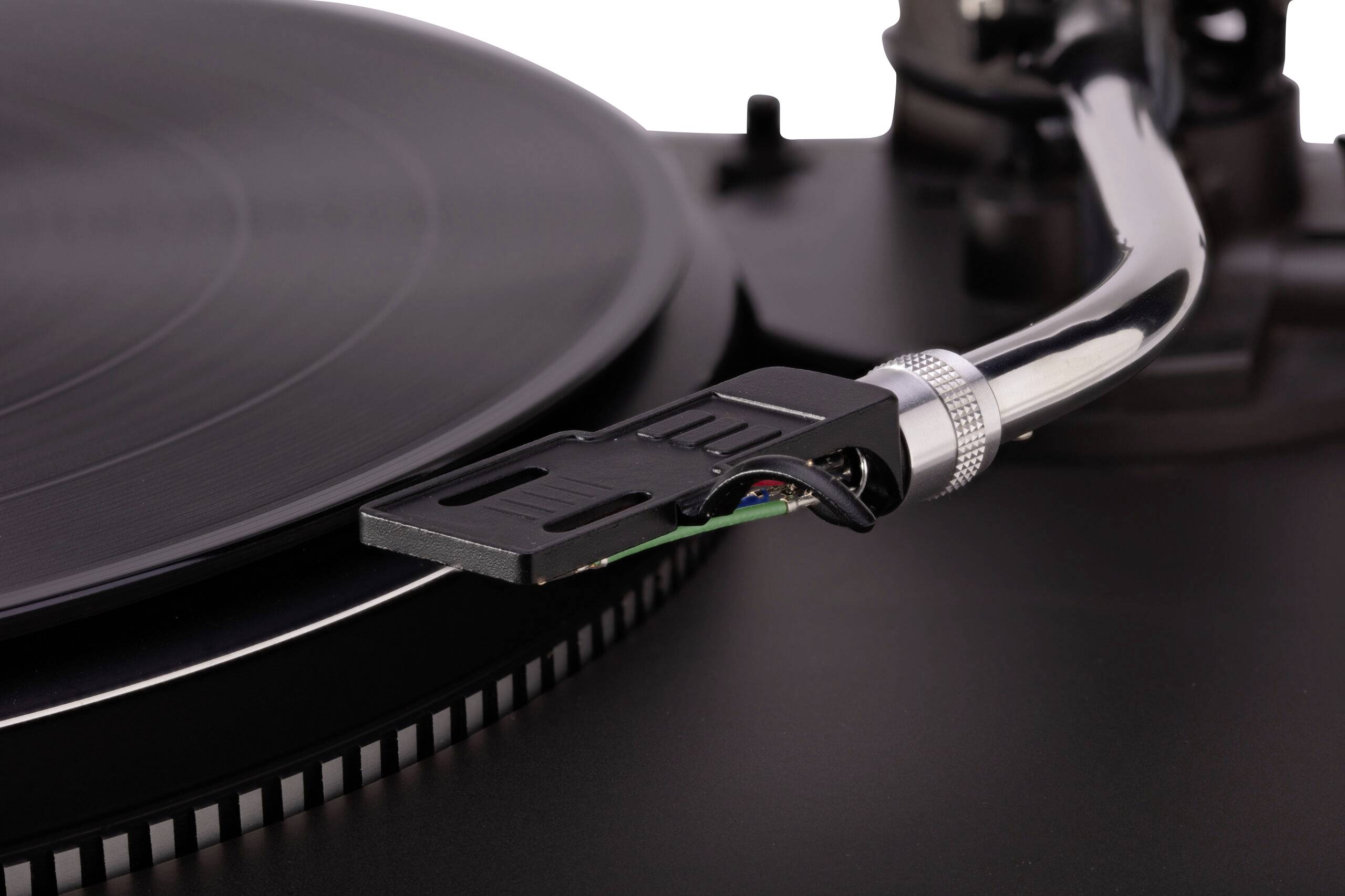 Un gros plan d'un tourne-disque vinyle avec une cellule de lecture positionnée sur un disque vinyle noir en rotation.