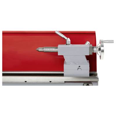 Tour à métaux avec un porte-pièce, placé sur un fond rouge, équipé d'un volant et de leviers de commande, utilisé pour maintenir des pièces pendant l'usinage.