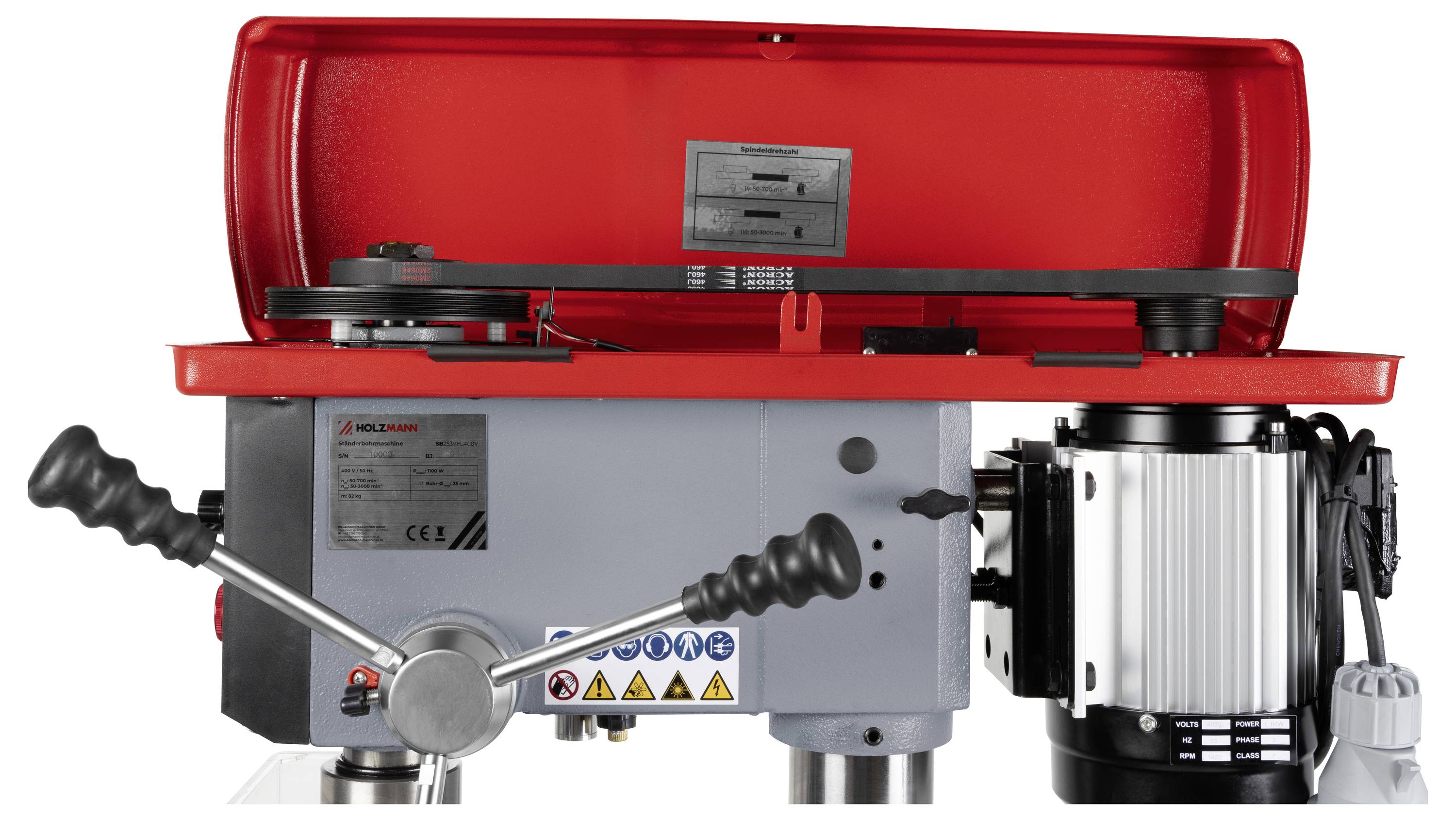 Une machine industrielle rouge et grise avec des leviers et un moteur, utilisée pour des opérations mécaniques, comportant des étiquettes d'avertissement sur son corps.