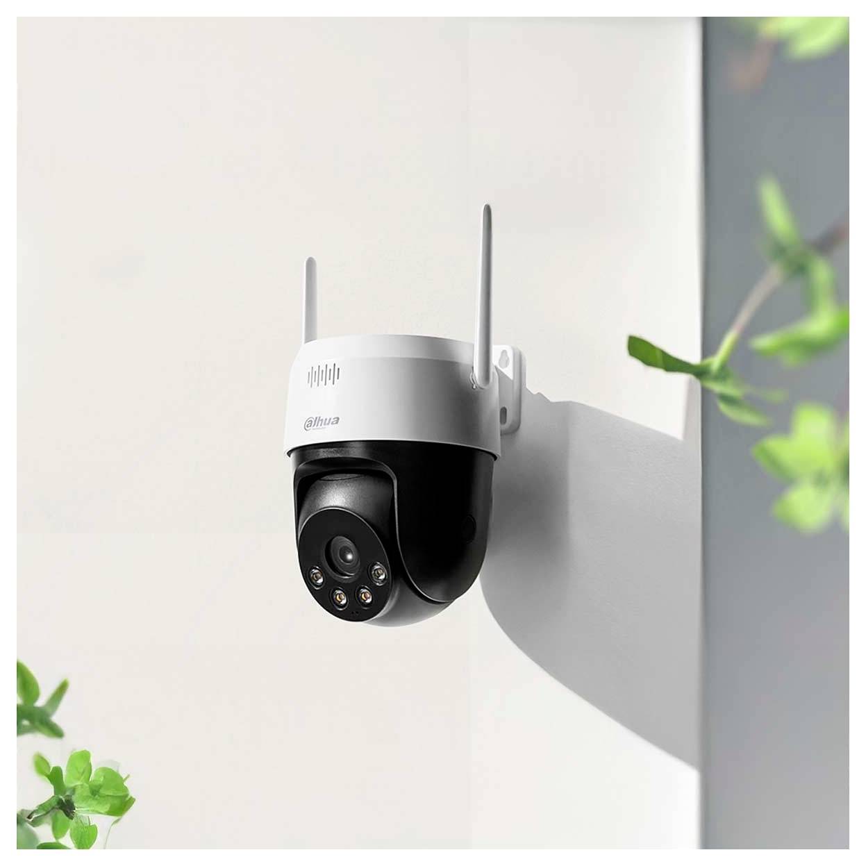 Une caméra de sécurité montée sur un mur, équipée d'antennes et de lumières infrarouges. Elle est positionnée à l'extérieur, entourée de verdure floue.